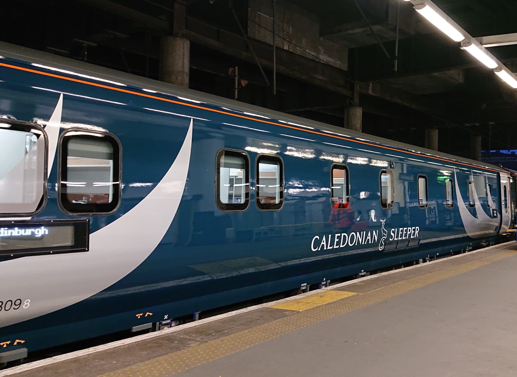 A Caledonian Sleeper Mark 5 sleeper coach in its dark blue livery with thistle branding
